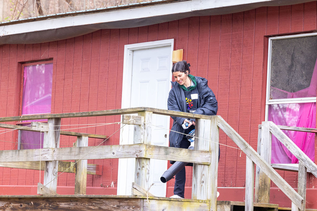 Keuka College student volunteer using leaf blower